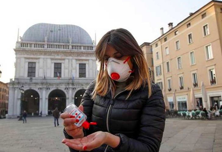 Mujer con mascarilla utilizando gel desinfectante de manos